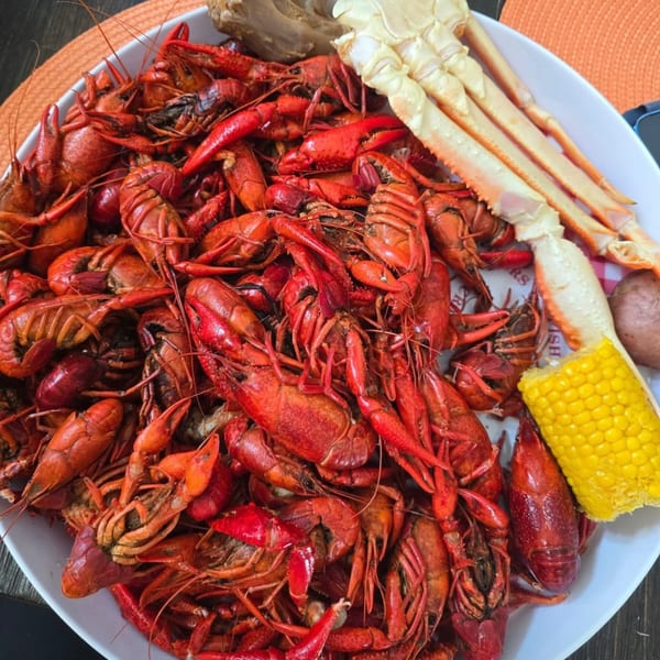 A large platter of Dat Bayou Spot's Cajun crawfish boil with crab legs, corn, and potatoes.