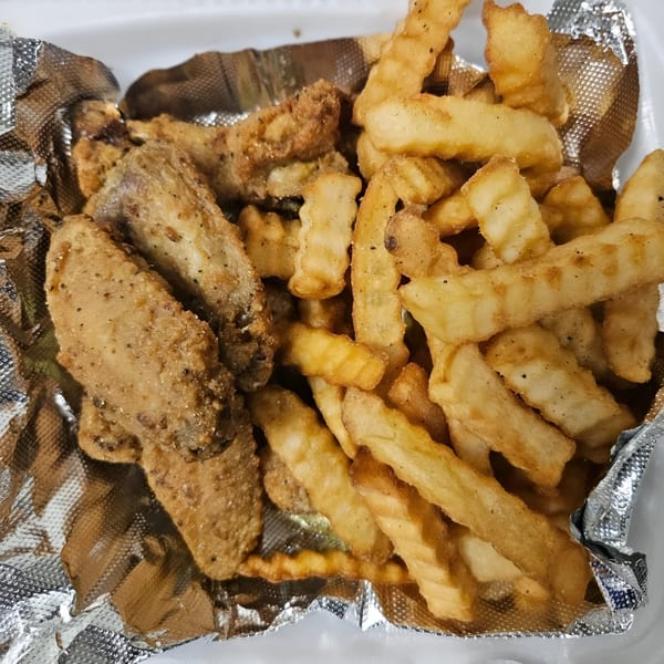 Fried chicken wings and crinkle-cut fries in a foil-lined container from Dat Bayou Spot.