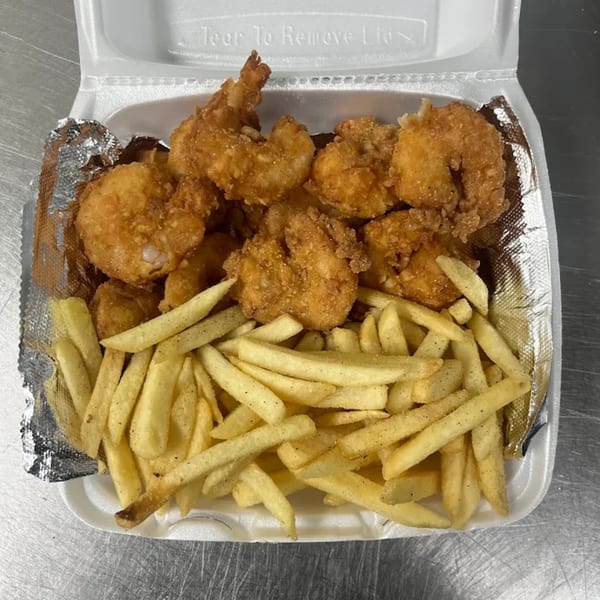 A white takeout container filled with golden-brown fried shrimp and seasoned french fries from Dat Bayou Spot.