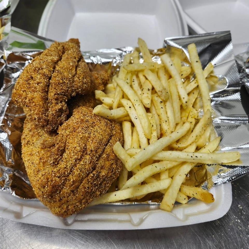 Dat Bayou Spot's fried catfish and seasoned french fries in a to-go container.