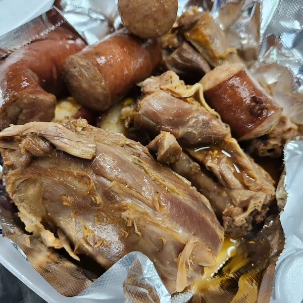 Close-up of Dat Bayou Spot's cajun boudin sausage and tender meat in a foil-lined container.